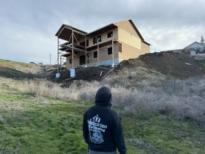 LF Construction crew member in a company hoodie facing a framed hillside home