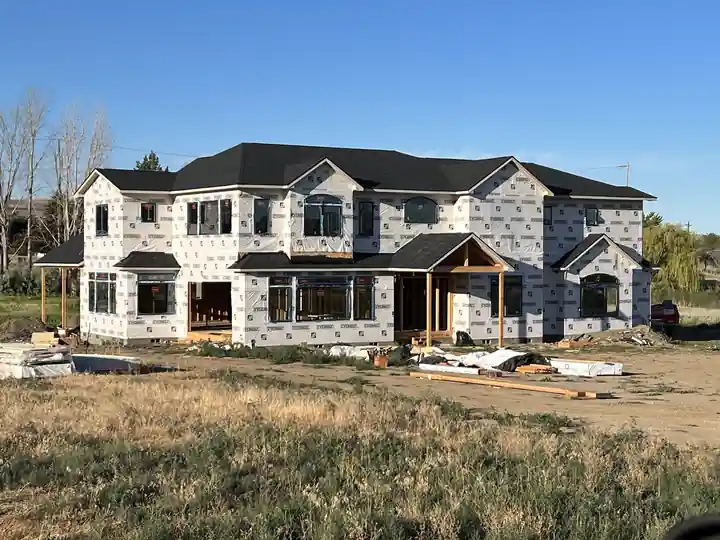 Two-storey custom home in housewrap with a timber porch, built by LF Construction