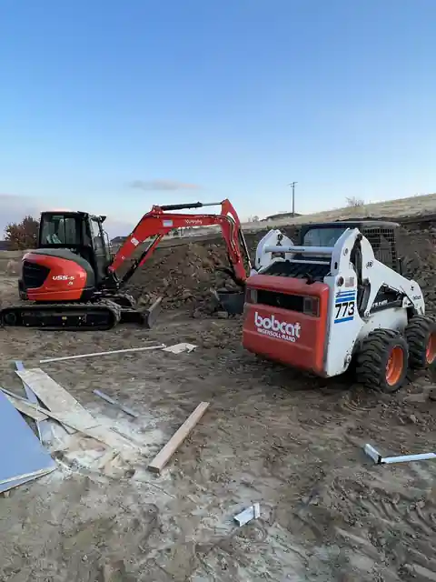 Orange excavator and a skid steer parked on a job site