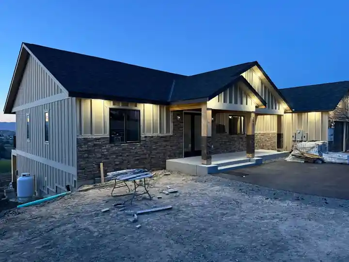 The same house finished at dusk, porch posts and soffit lights lit