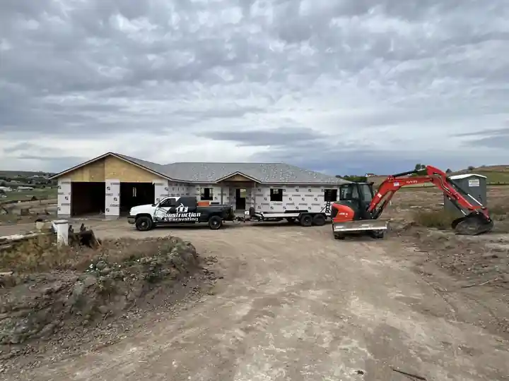 White LF truck and an excavator in the yard of a home with its shell up