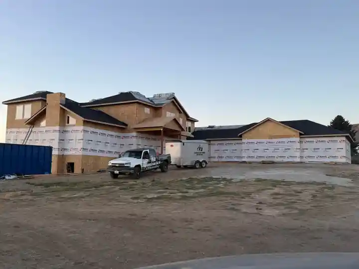 Large two-storey home in housewrap with an LF truck and trailer out front