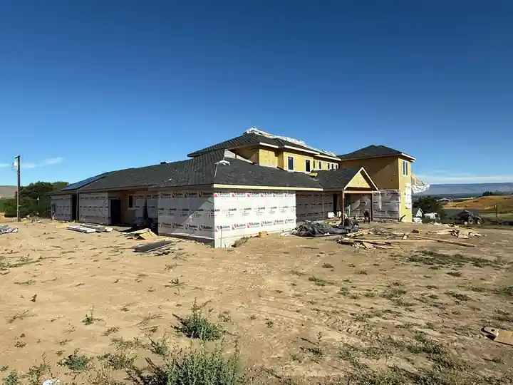 The same large home roofed, with housewrap going on