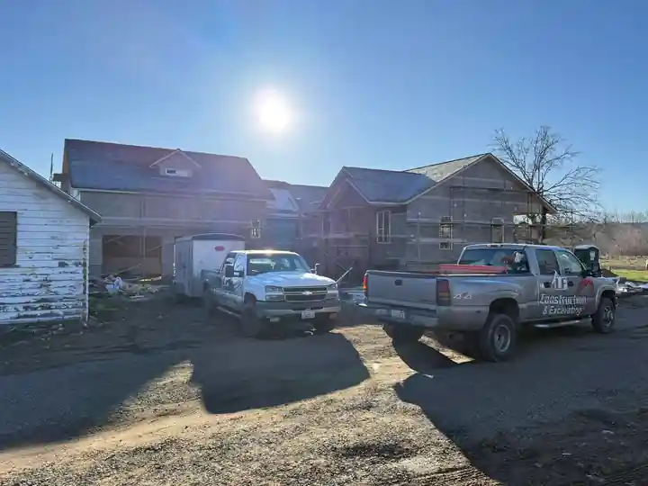 Two LF Construction trucks parked at an older house being rebuilt