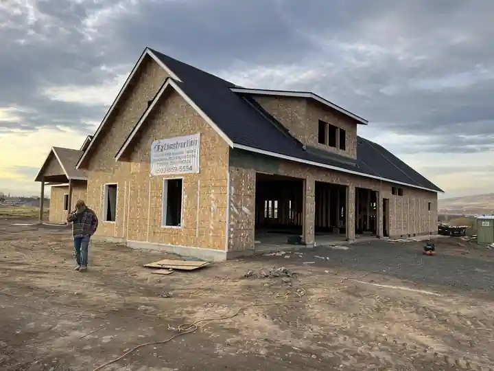Roofed home with an LF Construction job sign and a crew member walking the site