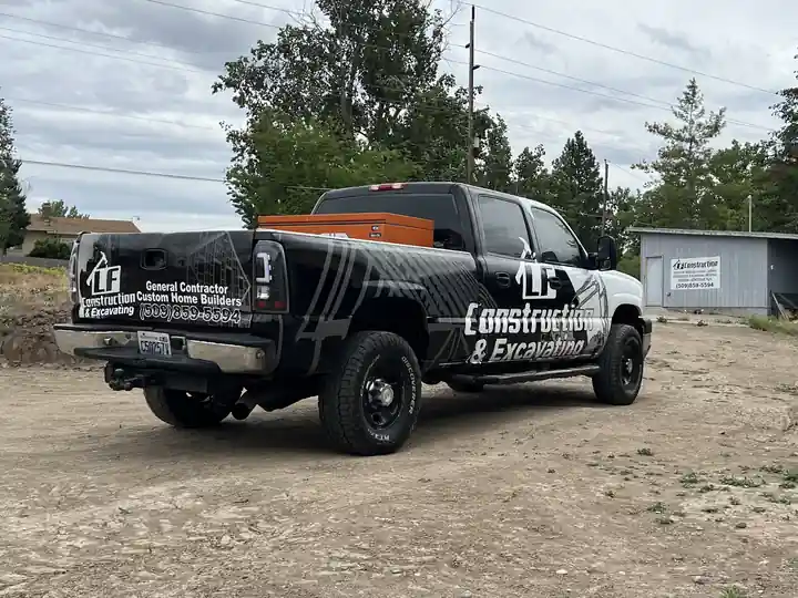 Black LF Construction pickup with a wrap reading General Contractor, Custom Home Builders