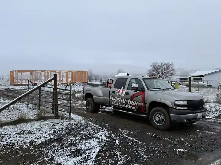 Silver LF Construction pickup in the snow with a framed shell behind it